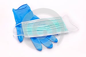 Pair of medical blue latex protective glove and green mask on white background. Protection equipment against virus, flu.