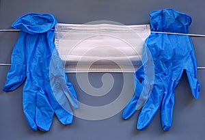 Pair of medical blue latex protective glove and white mask on gray background. Protection equipment against virus, flu.