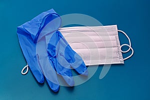 Pair of medical blue latex protective gloves and white mask on blue background. Protection equipment against virus, flu.