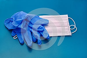 Pair of medical blue latex protective gloves and white mask on blue background. Protection equipment against virus, flu.