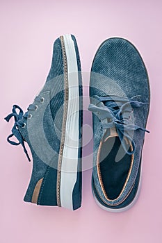 A pair of men`s sneakers. Blue denim shoes on a pink background. Comfortable textile footwear. View from above. Casual fashion