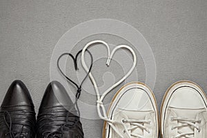 A pair of men`s sneakers and women`s shoes in love. Laces in the shape of a heart. Family and love concept. Valentines day