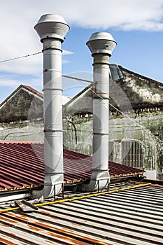 A pair of metallic chimneys on a roof top of a factory