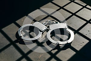 Metallic handcuffs on surface, sharp shadows, grid like shadow pattern photo