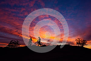 Mountain bikers silhouetted against a colorful sunset sky in South Mountain Park, Phoenix, Arizona. photo