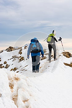 Pair of mountaineers ascending a snow covered mountain ridge.
