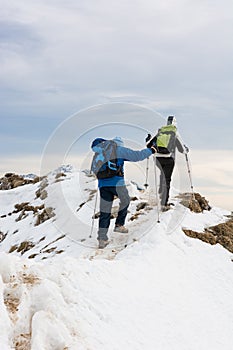 Pair of mountaineers ascending a snow covered mountain ridge.