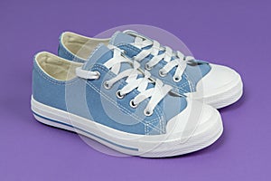 Pair of new blue sneakers, sport shoes on purple background