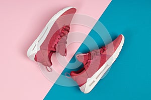 Pair of new pink sneakers, sport shoes on blue and pink background. Pink womens sport, running shoes
