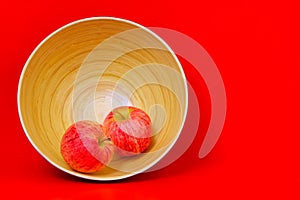 Pair of new zealand red apples in a bamboo pot against  red background