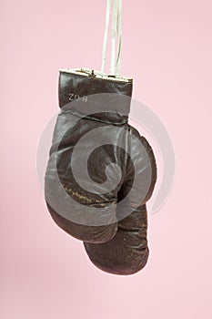 a pair of old boxing gloves hung in front of a candy-pink background