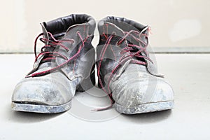 Pair of old dirty work boots in building site