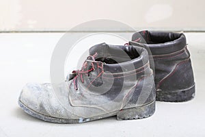 Pair of old dirty work boots in building site