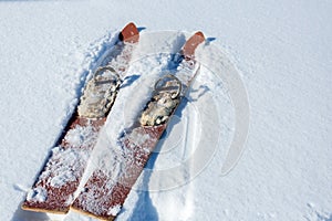 Pair of old fashioned wooden red skis on white snow