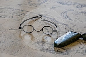 Pair of old glasses or spectacles on top of marine map