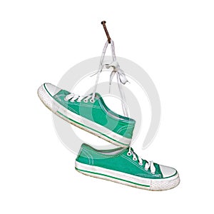 Pair of old green sneakers hanging on rustic nail isolated