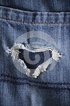 Pair of old jeans with heart shaped rip