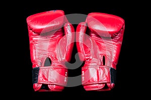 A pair of old red boxing gloves on a black background.