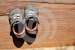 A pair of old shoes a brown wooden board.