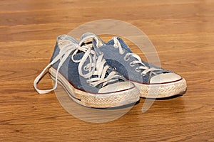 Pair of old worn sneakers on a wooden floor