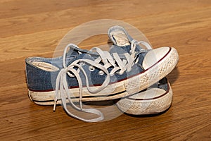 Pair of old worn sneakers on a wooden floor