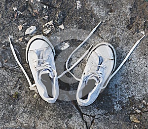 Pair of old worn white sneakers with laces