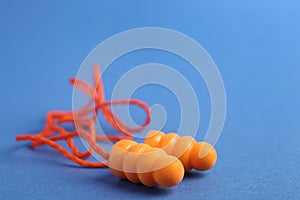 Pair of orange ear plugs with cord on blue background, closeup. Space for text