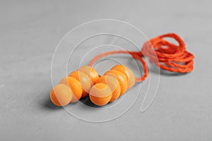 Pair of orange ear plugs with cord on grey background, closeup