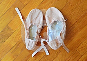 A pair of pink ballet shoes on parquet flooring