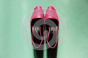 Pair of pink lady shoes on green background