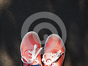 a pair of pink sneakers on the wet asphalt