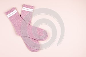 Pair of pink socks with white strips on pastel pink background with copy space