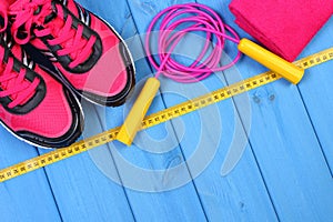 Pair of pink sport shoes and accessories for fitness on blue boards background, copy space for text