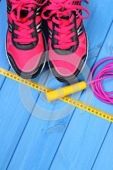 Pair of pink sport shoes and accessories for fitness on blue boards, copy space for text