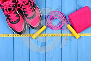 Pair of pink sport shoes and accessories for fitness on blue boards, copy space for text