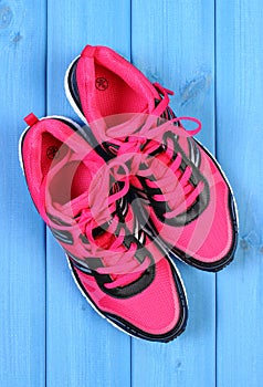 Pair of pink sport shoes on blue boards background