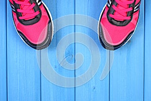 Pair of pink sport shoes on blue boards background, copy space for text