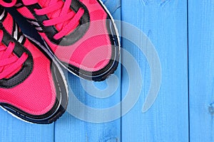 Pair of pink sport shoes on blue boards, copy space for text