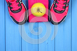 Pair of pink sport shoes and fresh apple on blue boards, copy space for text