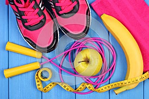 Pair of pink sport shoes, fresh fruits and accessories for fitness on blue boards