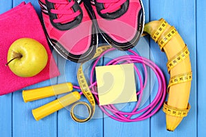 Pair of pink sport shoes and fresh fruits on blue boards, copy space for text on sheet of paper