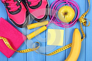 Pair of pink sport shoes and fresh fruits on blue boards, copy space for text on sheet of paper