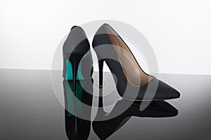 pair of pointed woman shoes with black soles blue high heels