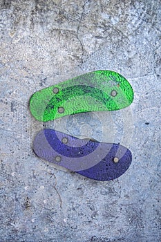 a pair of purple and green flip-flops placed upside down