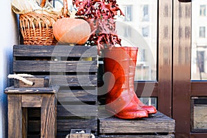 a pair of red boots on a wooden box on the background of a wall and pumpkins