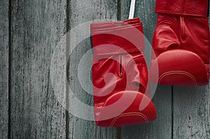 Pair of red boxing gloves on an old shabby wooden wall