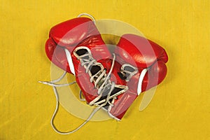 Pair of red boxing gloves, worn out, with laces untied