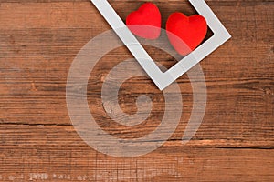 Pair of red hearts in white frame on vintage wooden table, top view. Saint Valentines day background