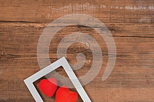 Pair of red hearts in white frame on vintage wooden table, top view. Saint Valentines day background