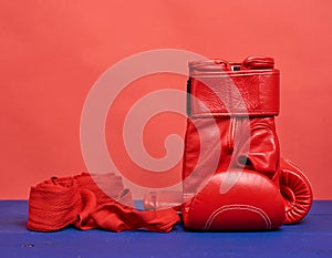 Pair of red leather boxing gloves on a blue background, sports equipment